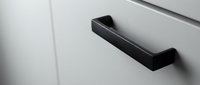 Modern black cabinet handle on white furniture door creates sleek minimalist design for contemporary kitchen or bathroom interior renovation projects.