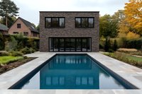 Modern brick house with swimming pool in backyard, surrounded by autumn trees and landscaped garden. Luxury residential architecture.