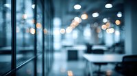 Blurred modern office interior with glass partitions and bokeh light effect creating atmospheric corporate environment.