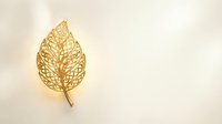 Golden filigree leaf with intricate cutout pattern on cream background for luxury design projects and elegant branding materials.