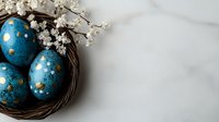 Decorative blue Easter eggs with gold polka dots nestled in natural twig nest, accompanied by delicate white spring cherry blossoms against marble background.