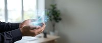 Businessman holding glowing digital hologram with data visualization and futuristic interface elements in modern office environment for technology presentations.