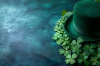 Green leprechaun hat surrounded by fresh shamrock leaves on dark textured background with mystical atmosphere and copy space for St Patrick's Day celebration.