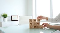 Businessman hands arranging wooden blocks with heart icons on modern office desk for customer service and care concept.