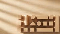 Wooden geometric shape sorting toy with blocks on natural wood surface with soft shadow patterns for educational play and development.