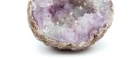 Amethyst geode with purple crystalline interior and natural tan exterior, isolated on white background for design and educational use.