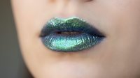 Closeup of lips with shimmering turquoise and green metallic makeup, showcasing bold cosmetic artistry and creative beauty trends for makeup tutorials and fashion editorials.