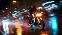 Motorcyclist riding at night through urban streets with motion blur and colorful city lights reflecting on wet pavement.