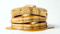 Stack of fluffy pancakes with melted butter and maple syrup dripping down sides, perfect for breakfast, brunch, and food photography projects.