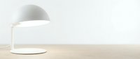 Modern white desk lamp with curved dome shade on wooden surface, minimalist interior design element for home office and contemporary workspace styling.