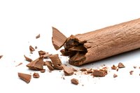 Broken chocolate bar with scattered pieces and crumbs on white background, crushed sweet dessert ingredient for baking and confectionery.