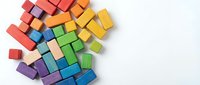 Colorful wooden building blocks scattered on white background creating playful educational toy arrangement for children development and learning activities.