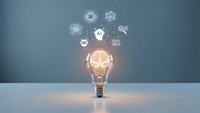 Glowing light bulb with brain inside surrounded by innovation icons representing creativity, artificial intelligence and business technology solutions.