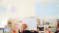 Man in business suit holding blank white card with blurred office background, corporate identity mockup for branding and advertising purposes.