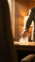 Businessman touching glowing upward arrow chart on desk in warm office lighting, representing growth, success, and financial progress for corporate business concepts.