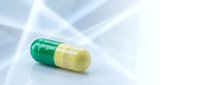 Green and yellow pharmaceutical capsule pill on clean white surface for medical healthcare and medication concepts.