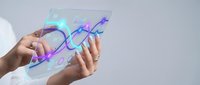 Hands holding transparent futuristic tablet displaying holographic interface with glowing elements for technology and innovation concepts.