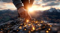 Hand touching illuminated rock surface at sunset with mountain landscape in background, creating magical connection with nature.