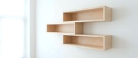 Modern wooden floating shelves mounted on white wall creating minimalist storage solution for contemporary home decor and organization.
