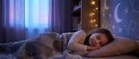 Young woman sleeping peacefully in cozy bedroom with moon and stars night light creating dreamy atmosphere for rest and relaxation.