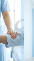 Nurse in blue scrubs gently holds patient hand in hospital, showing compassion, care, and emotional support in medical setting.