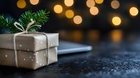 Wrapped gift box with evergreen sprig and white ribbon on dark surface with warm bokeh lights creating festive holiday atmosphere for seasonal celebrations.