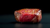 Juicy medium rare beef steak with crispy seared crust and seasoning on dark background, close up view showing pink center and caramelized exterior.