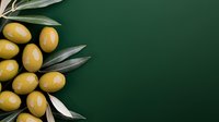 Fresh yellow olives with green leaves arranged on dark green background, copy space for text, top view composition for food photography and design.