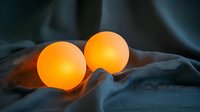 Glowing orange spherical lights creating warm ambient illumination on dark fabric background, soft mood lighting for atmospheric interior design.