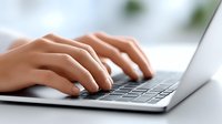 Close-up of female hands typing on modern laptop keyboard in bright office environment for business productivity and remote work applications.