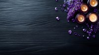 Aromatic spa composition with glowing candles and purple lilac flowers on dark wooden background, creating peaceful wellness atmosphere.