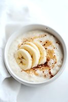 Fresh banana slices on creamy yogurt sprinkled with cinnamon in white ceramic bowl against light background, healthy breakfast concept.