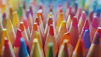 Vibrant colored pencils arranged in rows creating abstract pattern with shallow depth of field, tips pointing upward in rainbow hues against blurred background.