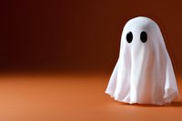 Cute white ghost figure on orange background with dramatic lighting and soft shadows. Classic Halloween decoration with minimalist spooky character design.