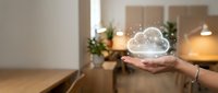 Hand holding glowing cloud with network connections in modern office space representing cloud computing and digital transformation technology.