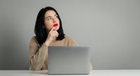 Thoughtful young woman with laptop computer looking up while thinking, business professional contemplating ideas at workplace.