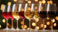 Wine glasses filled with red, white and rose varieties against warm bokeh lights background, elegant celebration setup for wine tasting or party event.