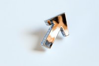Metallic silver arrow pointing upward on white background, casting soft shadow. Modern minimalist design element for business and financial concepts.