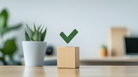 Green checkmark on wooden cube with succulent plant in white pot on desk, minimalist office workspace setting for business concepts and task completion.
