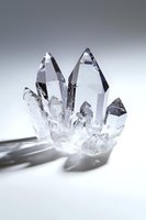 Clear quartz crystal cluster formation with sharp points and natural geometric shapes casting soft shadows on white surface. Spiritual healing concept.