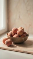 Fresh peaches arranged in rustic wooden bowl on marble surface near window, ideal for food styling, culinary content, and kitchen decor projects.
