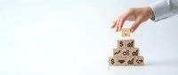Business professional hand stacking wooden blocks with financial growth symbols and dollar signs on white background for investment concepts.