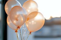 Soft peach and white party balloons catching golden sunlight create dreamy atmosphere at sunset, festive celebration mood with helium-filled latex decorations.