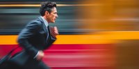 Businessman in dark suit running with motion blur effect, conveying urgency and speed in urban environment.