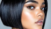 Close up portrait of young South Asian woman with short black bob hairstyle, natural makeup, glossy lips and flawless glowing skin against light background.