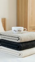 Cozy home concept with a white ceramic cup on folded soft blankets in neutral tones, warm hygge lifestyle and comfort interior.