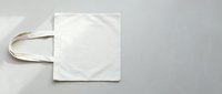 Blank white cotton tote bag with natural handles isolated on gray background, ready for custom design, branding, printing, and merchandise mockup projects.