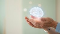 Human hands holding glowing brain hologram representing artificial intelligence, neuroscience research, mental health awareness and cognitive technology innovation.