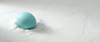 Turquoise robin egg nestled in soft white feathers creating serene natural composition for spring and Easter themed designs.