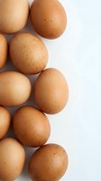 Fresh brown chicken eggs arranged on white background for cooking and baking ingredients in kitchen recipes and healthy organic food preparation.
